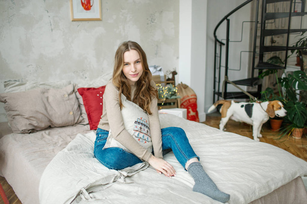 Young beautiful curly hair brunette woman in jeans on bed - Foto, afbeelding