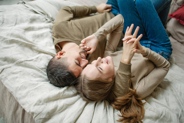 Young caucasian couple having fun on bed indoors - 写真・画像