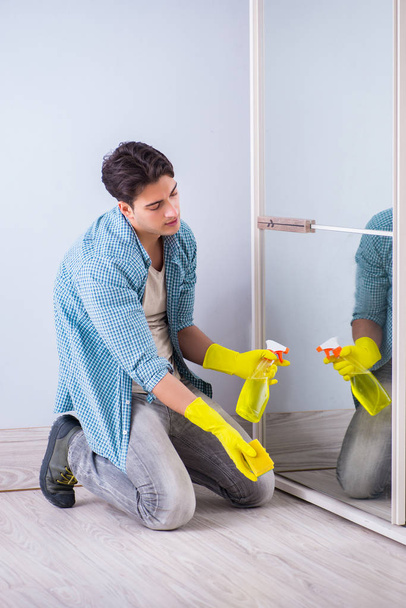 Jeune homme nettoyage miroir à la maison hôtel - Photo, image