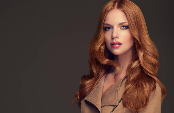 κόκκινα μαλλιά κορίτσι με σγουρά μαλλιά μακριά και λαμπερά. Το όμορφο μοντέλο γυναίκα με σγουρά hairstyle. Φροντίδα και την ομορφιά των μαλλιών - Φωτογραφία, εικόνα
