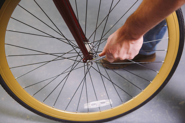 テーマ修理バイク。白人男の手のクローズ アップ手ツール自転車ツール ハブ コーンもぎとるを調整し、赤い自転車のクイック リリースとを介して車軸をインストールに使用してください。 - 写真・画像