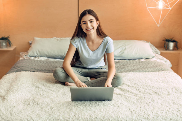 Adorable teenage girl smiling while using her laptop - Valokuva, kuva