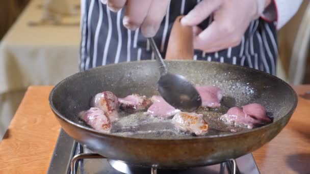 Close-up van chef-kok koken geflambeerd stijl schotel met plakjes lever op een hete koekenpan in restaurant. Roeren met een lepel. Slow motion. - Video