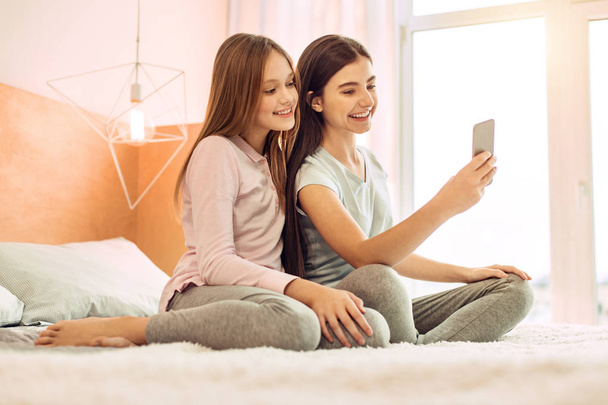 Two cute sisters taking selfies on bed - Foto, immagini