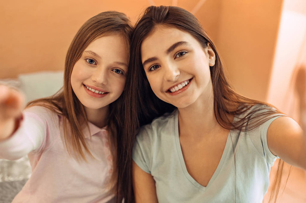 Upbeat teenage sisters taking a picture together - Foto, afbeelding