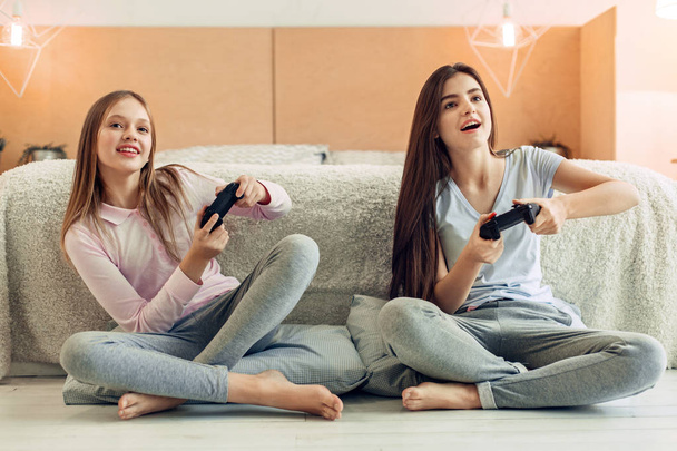 Two teenage sisters playing video game in bedroom - 写真・画像