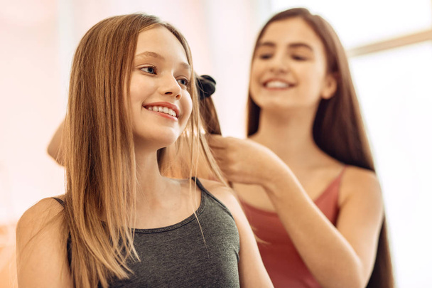 Pretty girl having her hair straightened by sister - Foto, immagini