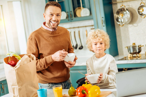 Positive joyful father and son eating breakfast - Фото, зображення