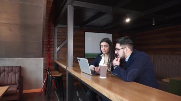Двое коллег обсуждают работу в кафе с ноутбуком и кофе за столом
 - Кадры, видео