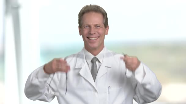 Cheerful doctor put on stethoscope on his neck. - Video