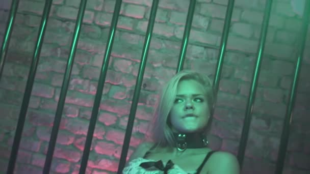 Hot young long hair blonde girl in black lingerie seductive moves in metal cage - Imágenes, Vídeo