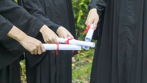 personnes avec des robes de graduation noires détiennent un diplôme
. - Photo, image