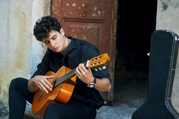 Young man playing guitar in the yard . Street musician - Fotoğraf, Görsel