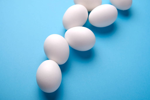 Fresh white eggs over blue background, top view. - Foto, Imagem