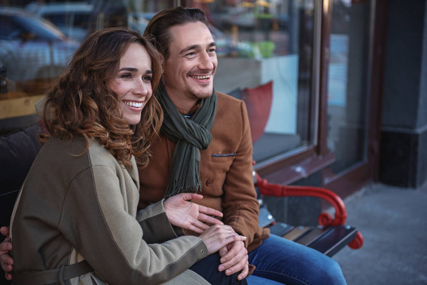 Happy man and woman resting on bench in city - Zdjęcie, obraz