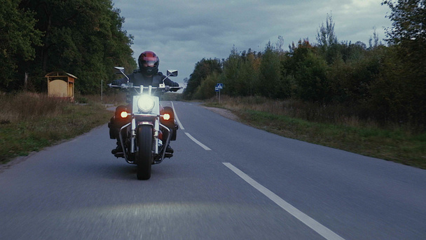 Um homem monta uma motocicleta por uma estrada na floresta
 - Foto, Imagem