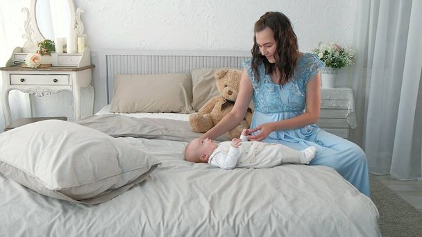 Követés anya üzembe baba aludni járás közben. Vonzó nő gazdaság baba kéz és a séta az egész nappali jó ablak függönyt háttérben. - Fotó, kép