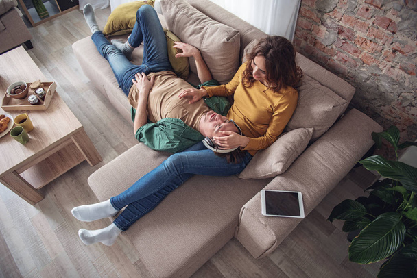 Happy man and woman relaxing in living room - Foto, afbeelding
