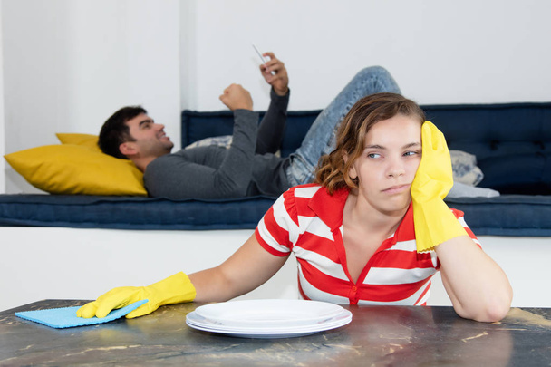 Frustrated woman cleaning room with lazy man - Фото, зображення