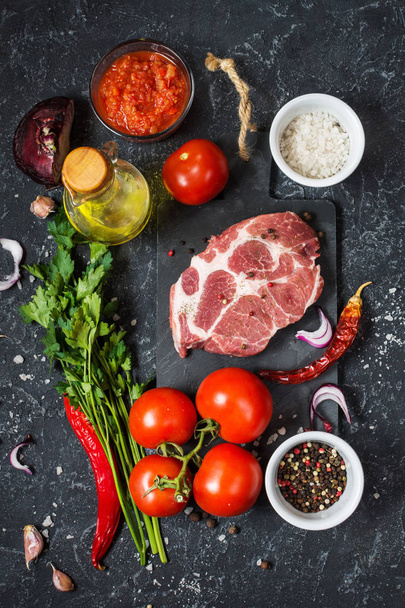 Raw marbled meat steak with ingredients for cooking on dark stone background - Foto, Imagen