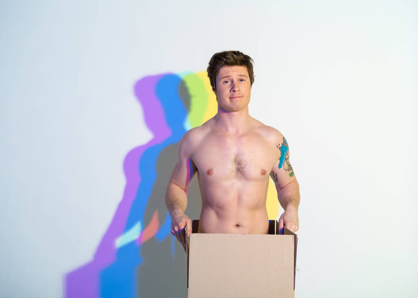 Cheerful naked male locating in box - 写真・画像