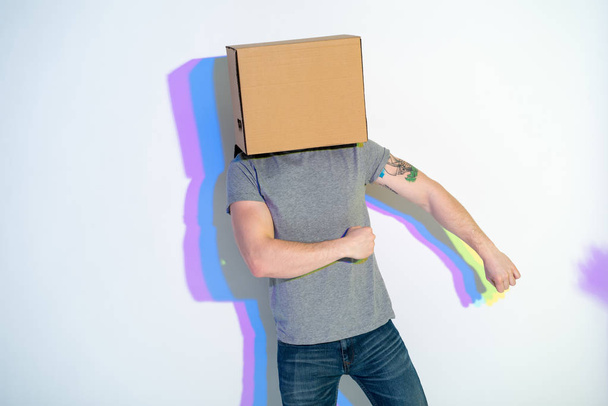 Man with carton on head flourishing arms - Foto, afbeelding