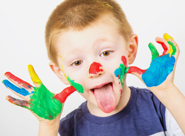 smiling little boy with hands painted in colorful paints - Fotó, kép