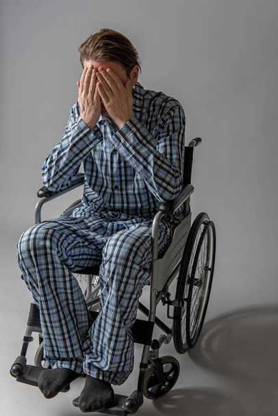 Pessimistic cripple in chair covering his face with hands - Фото, зображення