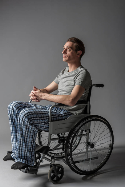 Pensive young disabled sitting in wheelchair - Foto, Bild