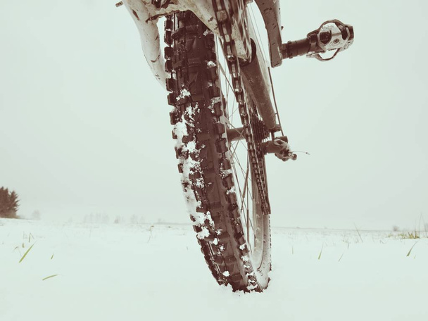 Low ankle photo of rear hweel of mtb in snowdrift. Picture taken within winter bike trip - Photo, Image