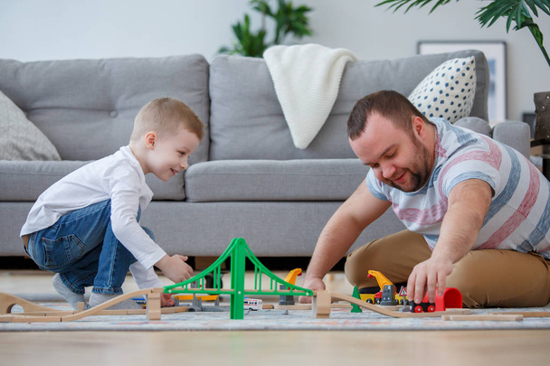 Family image of father and son playing on floor in toy road with cars - Foto, Imagen