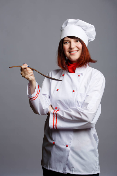 Picture of woman cook in white coat and cap with wooden spoon - Foto, immagini