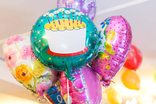 party, decoration, surprise concept. there is great bouquet of blowed up colorful baloons with different patterns like flowers and big birthday cake with candles - Foto, Imagem