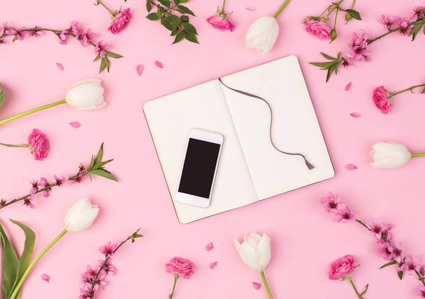 businesswoman, connection, industrial life concept. wonderful flatlay composed of the mobile phone and clean daily planner surrounded with different flowers such as tulips, roses, oriental cherry - Fotó, kép