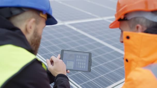 4K Technicians with tablet checking the panels at solar energy installation - Felvétel, videó