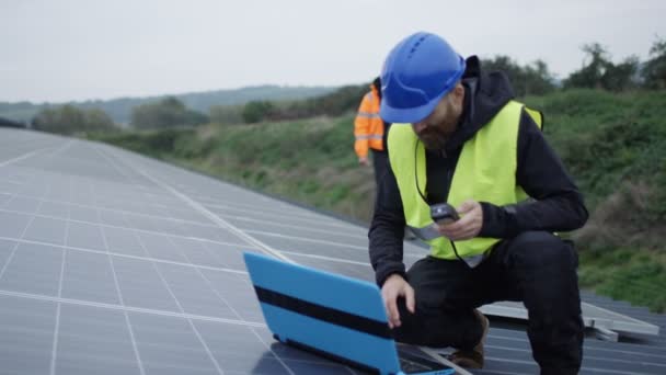 4K One technician with laptop checking the panels at solar energy installation - Imágenes, Vídeo