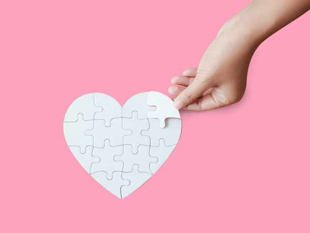 Close up shot hand of woman playing heart shape jigsaw puzzle on - Фото, зображення