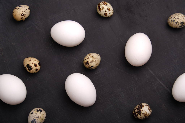Chicken and quails eggs on black background. - Photo, image