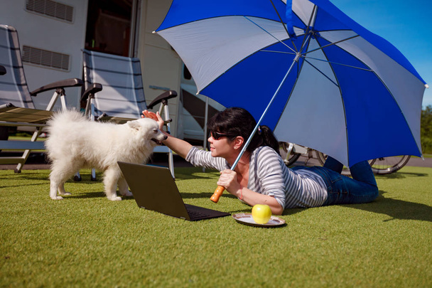 Mujer en la hierba con un perro mirando un portátil
 - Foto, Imagen