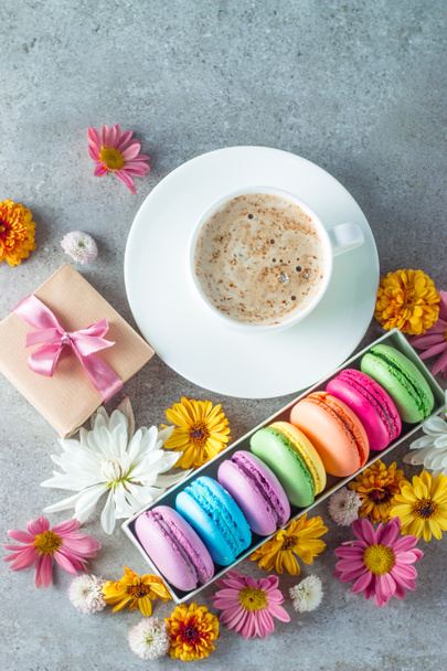Foto de macarons bolo, caixa de presente, chá, café, cappuccino e flores. Doce conceito macaroon comida romântica. Manhã café da manhã e presentes
. - Foto, Imagem