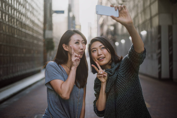 Two japanese women around in Tokyo during daytime. Making shoppi - Photo, Image