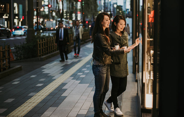 Two japanese women around in Tokyo during daytime. Making shopping and having fun - Photo, Image