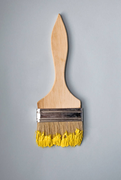 Escova de madeira sobre um fundo azul. Tinta amarela
. - Foto, Imagem