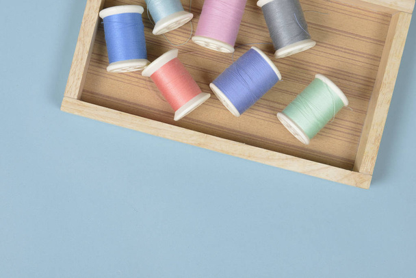 Flat lay of colored thread rolls for sewing on blue background,  - Фото, изображение