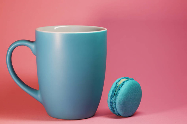 Blue tea cup on pink background with macaroons - Фото, зображення