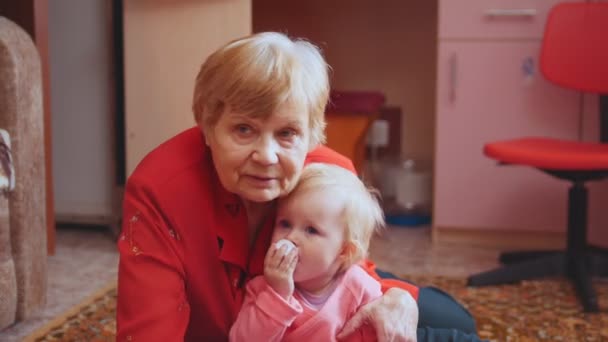 Malá dívka si hraje s její babičkou na podlaze, babička objímání a líbání vnučka - Záběry, video