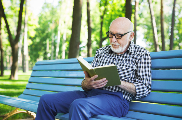 Пожилой человек в случайном чтении на открытом воздухе
 - Фото, изображение