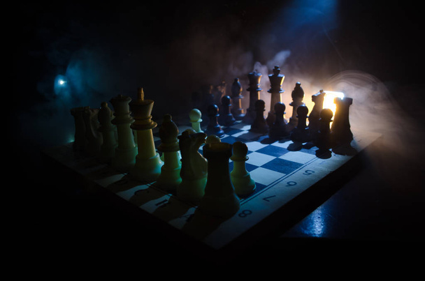Šachy desková hra koncept podnikatelských nápadů a precizní strategie a soutěž myšlenek. Šachové figury na tmavém pozadí se kouře a mlhy. - Fotografie, Obrázek