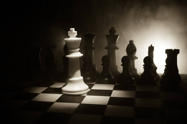 tablero de ajedrez concepto de juego de ideas de negocios y la competencia y las ideas de estrategia cóncep. Figuras de ajedrez sobre un fondo oscuro con humo y niebla
. - Foto, Imagen