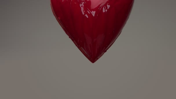 Kırmızı ıslak kalp kırmızı şeffaf sıvı ile havada uçan kaplı ve dökme üstünde o - Video, Çekim